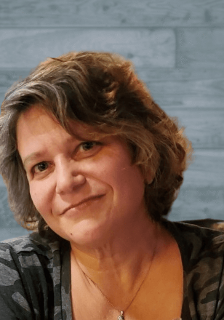 Smiling woman with short brown hair against a gray tiled background.